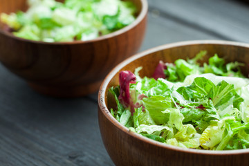 A dish of fresh salad frisse, Romano and radiccio with olive oil, salt and freshly ground percec in a wooden bowl