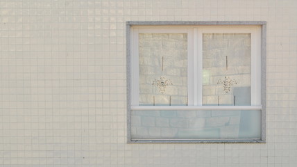 Janela recuperada, restaurada numa parede com azulejos brancos em volta
