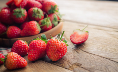 Fresh strawberries in a bowl on wooden background.
