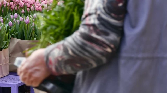 Tulips of different colors on the counter flower shop. closeup. A man passes by in a bright blue jacket