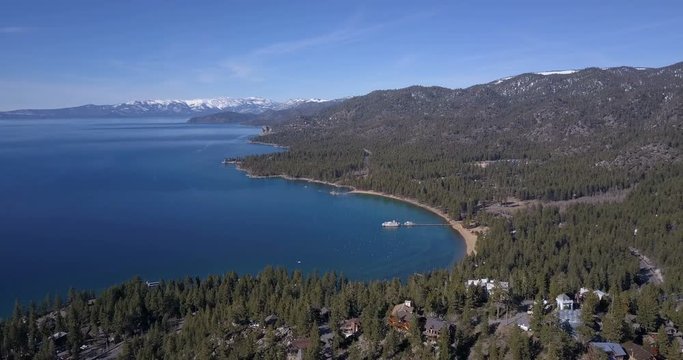 Aerial view of Lake Tahoe coastline and mountains covered by snow