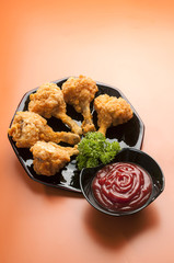 Chicken Lollypop on Black plate with parsley & catchup  