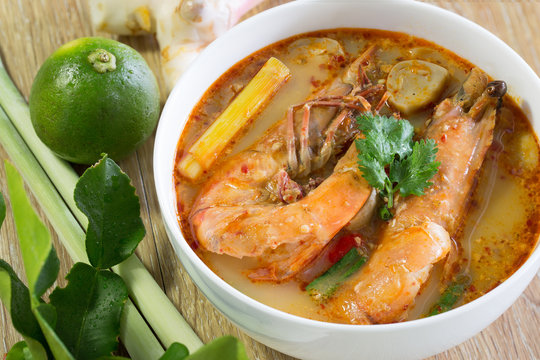 Tom yum kung in white bowl and ingredients on wooden table