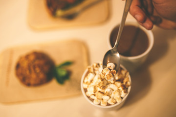 cocoa with marshmallows and cake on the table. Hand mixed drink