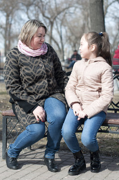 Mother with the daughter sit on a shop in the park.