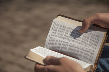 Young man holding and reading holy bible - obrazy, fototapety, plakaty