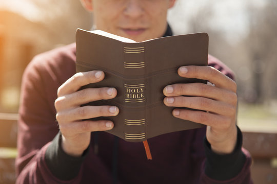 Young man holding and reading holy bible