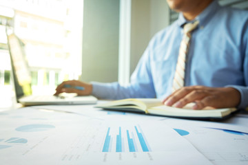 Business concept, Young business man's hands working with laptop and document graph on wood table.