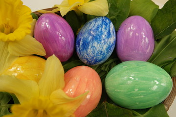 Multi-colored easter eggs in a basket with flowers