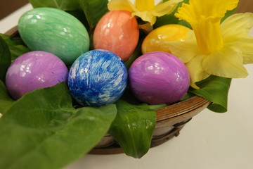 Fototapeta na wymiar Multi-colored easter eggs in a basket with flowers