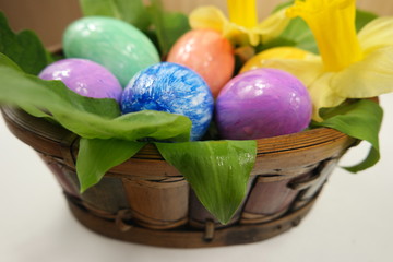 Multi-colored easter eggs in a basket with flowers