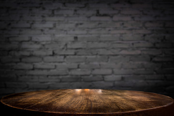Selected focus empty brown wooden table and wall texture or old black brick wall blur background...
