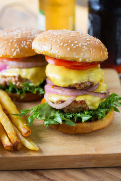 double cheese hamburger and french fries on wooden board