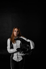 Portrait of redhead stylish woman in motorcycle equipment with biker black helmet look to the camera on black background. Girl in leather moto suit after race feel extreme life. Glad and happy female.