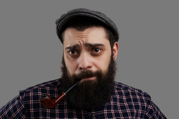 Disappointed bearded man with smoking pipe look to the camera in c heckered shirt. Person lost his job. Tired worker wait advice how to improve life level. Regret emotion on the male face.