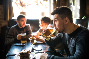 Man drink beer in front of to discussing drinking friends in pub. Friends in pub.