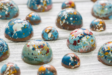 Chocolate handmade candy in the form of a planet. On a white wooden background