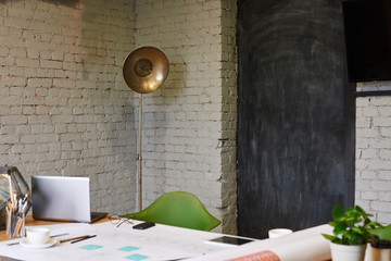 Architect interior with retro style lamp in corner. Design in grey, green, black colors. Working place of creative person in lunch time with soft focus on the desk with computer, architecture drawings