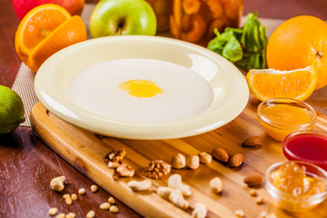 Semolina porridge with nuts, jam and fruits on wooden board