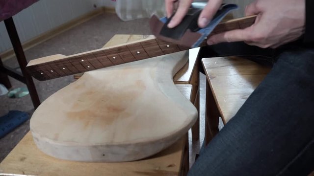 The master of repair of guitars repairs an electric guitar