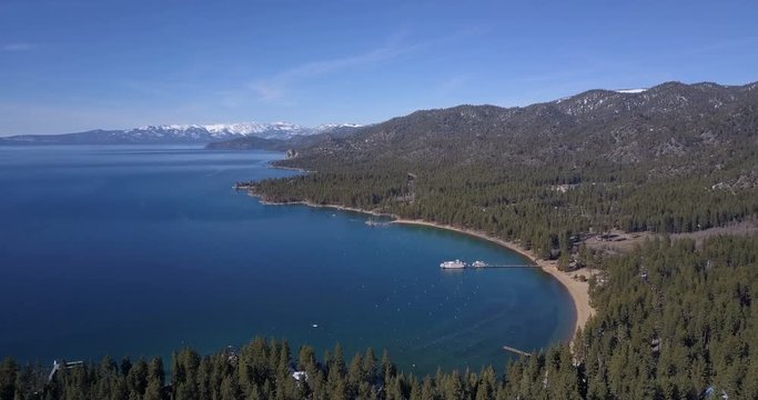 Aerial view of Lake Tahoe with paddle wheel boat moored in a bay, mountains covered by snow
