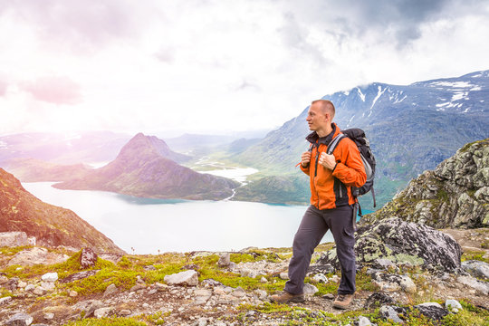 Young man hiking on Besseggen. Happy guy enjoy beautiful lake and good weather in Norway. Toning picture