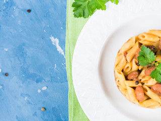 Served traditional Italian penne pasta with kidney beans on white plate and blue background