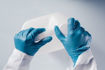 Chemical scientist opening white unlabeled plastic tank canister with chemicals