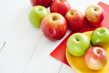 Apples on a yellow plate and white wooden surface closeup