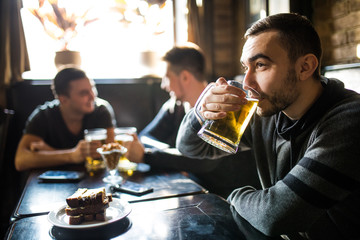 Man drink beer in front of to discussing drinking friends in pub. Friends in pub.