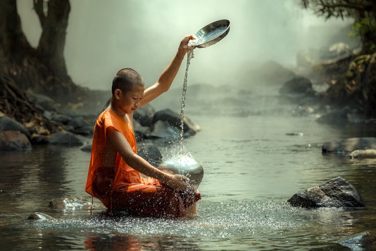 Thailand monk or novice monk sitting in the creek are wash container or bowl to clean - Powered by Adobe