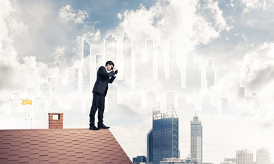 Businessman standing on roof and looking in binoculars. Mixed me