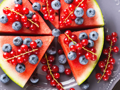 Slice of watermelon served as cake or pizza with fresh berries on rustic background