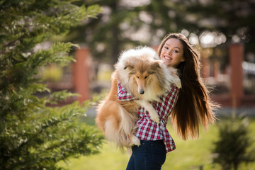 young beautiful woman with long hair walking with collie dog. Outdoors in the park.