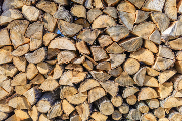 Chopped brown firewood, stacked and ready for winter. Stack of wood detailed background photo texture.