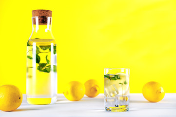 Cold water with lemon and mint on yellow background