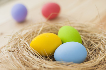 Easter eggs in nest on wood background