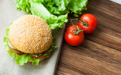 Bun with sesame and vegetables on a wooden background. Tomatoes and bread on the table.