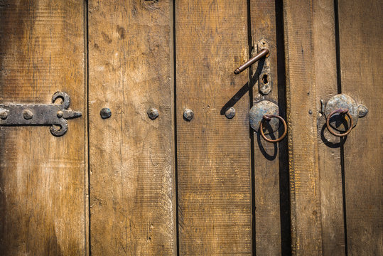 Detail of an old door handle. Rusting lock on an traditional door with paint peeling. Wooden background.