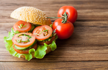 A sandwich with vegetables on a wooden background. Tomatoes and bread on the table.