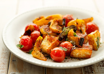 Naklejka premium Salad with grilled halloumi cheese and vegetable with addition of aromatic herbs on a white plate