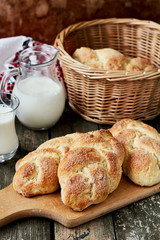 Sweet braided yeast bread on a wooden cutting board and a jug of milk