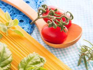 Italian spaghetti still life with fresh tomatoes and basil on checkered table cloth