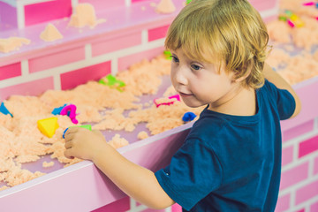 Boy playing with kinetic sand in preschool. The development of fine motor concept. Creativity Game...