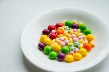 white plate with dragees and marmalade on white background