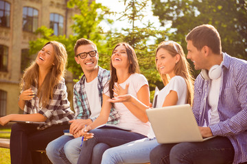 Happy young teens group sitting on bench and having fun