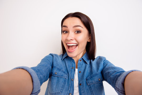 Portrait of excited cheerful smiling young pretty woman  in casual jeans shirt making selfie photo