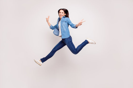Excited happy pretty  girl in casual jeans clothes high jump with raised hands and legs, on white background