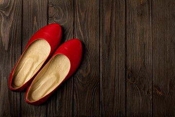 Red women's shoes (ballerinas) on wooden background.