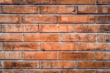 Old red brick wall with cracks and scratches. Horizontal wide brickwall background. Distressed wall with broken bricks texture. Vintage house facade.